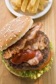 Hamburger mit Bacon, Ketchup und Pommes frites