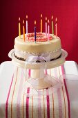 Birthday cake with burning candles on cake stand