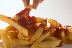 Hand nimmt Pommes frites mit Ketchup