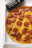 Pizza mit Salami und Käse im Pizzakarton mit Telefon