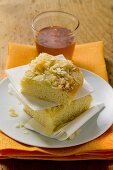 Two pieces of bee sting cake on plate in front of honey jar