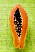 Halbe Papaya auf grünem Untergrund