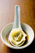 Pasta parcel on spoon in soy sauce
