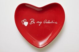 Red heart-shaped plate with the words Be my Valentine