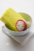 Brush and sponge in bowl on tea towel