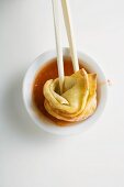 Ein frittiertes Wan Tan in süsssaure Sauce dippen