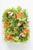Salad leaves with carrots and croutons in take-out box