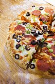 Pepperoni pizza with peppers and olives on wooden plate