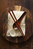 Dünne Reisnudeln auf Holzteller mit Essstäbchen und Löffel