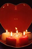 Brennende Kerzen und herzförmiger Teller für den Valentinstag