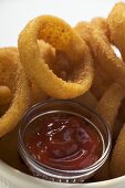 Deep-fried onion rings in white bowl, ketchup