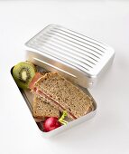Ham sandwiches, radish and kiwi fruit in lunch box