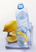 Mineral water in bottle and glass and lemon wedges