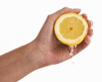 Frauenhand zerdrückt eine Zitrone