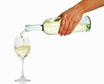 Frauenhand schenkt Weißwein ein