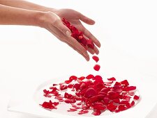 Hände baden in einer Wasserschale mit Rosenblättern