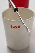 Becher mit 'love' Aufschrift und Fonduegabel