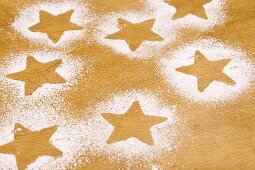 Star shapes outlined in icing sugar on wooden background