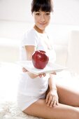 Junge Frau hält Teller mit einem Apfel