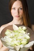 Red-haired woman with a bowl of white rose petals