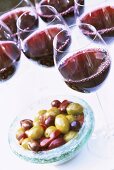 Glasses of red wine and a small dish of olives