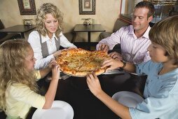 Family in restaurant sharing pizza