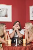 Two blond girls and a young man at a café table