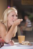 Young blond woman eating a piece of tiramisu