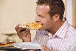 Man biting into a piece of pizza