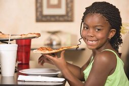 Mädchen im Restaurant isst ein Stück Pizza