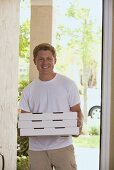 Mann steht mit Pizzakartons an der Haustür