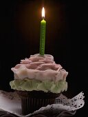 Ein Cupcake mit einer brennenden Geburtstagskerze