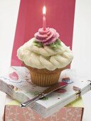 Ein Cupcake mit einer Geburtstagskerze auf Serviettenstapel