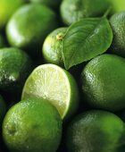 Limes, several whole and one halved (full-frame)