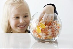 Blond girl reaching into a sweet jar