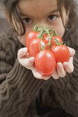 Mädchen hält Strauchtomaten an der Rispe