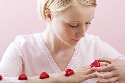 Young woman with red chocolate hearts on her arm