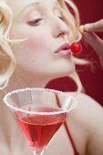 Young woman with Cosmopolitan eating a cherry