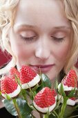 Junge Frau mit einem Strauss in Schokolade getauchte Erdbeeren