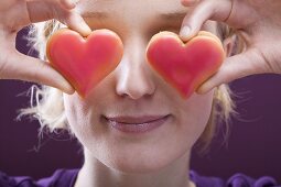 Young woman with two heart-shaped biscuits in front of her eyes