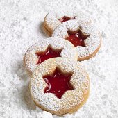 Four Linzer biscuits on icing sugar
