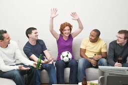 Friends with football and beer sitting in front of TV