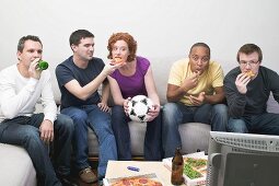 Friends sitting in front of TV with football, pizza & beer