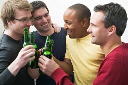 Vier Männer stossen mit Bierflaschen an