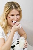 Young woman with football eating natural yoghurt