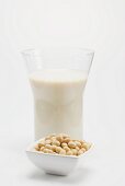 A glass of soya milk, small dish of soya beans in front