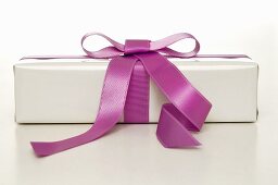 Gift in white wrapping paper with purple ribbon