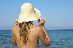 Frau mit Hut am Meer
