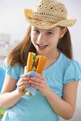 Girl in hat eating fish and salad sandwich at picnic