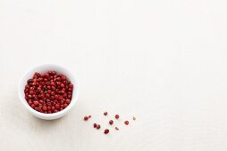 Pink peppercorns in and beside a small dish